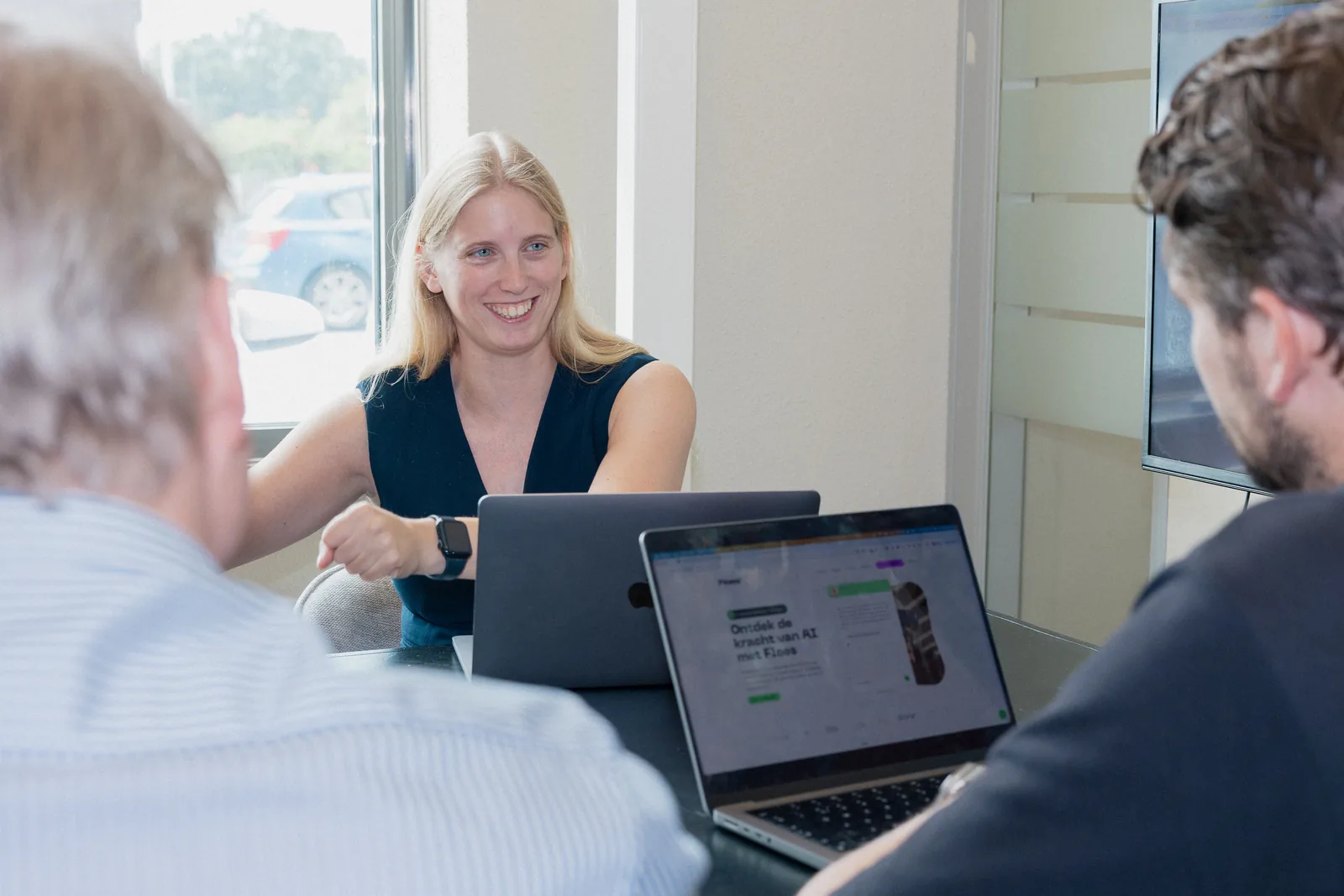 Collega's van PROMPTED overleggen achter een laptop op kantoor